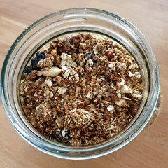 Closeup on Homemade Granola in Open Glass Jar on Wooden Table Background