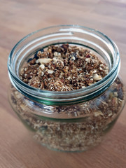 Homemade Granola in Open Glass Jar on Wooden Table Background