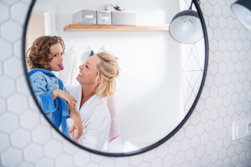 A reflection of mother and small daughter in mirror in bathroom.