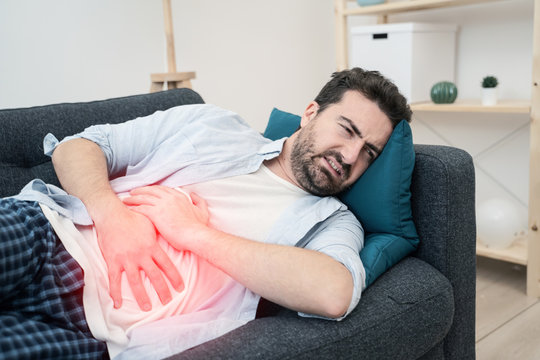 Man Lying On The Sofa Feeling Pain And Stomachache