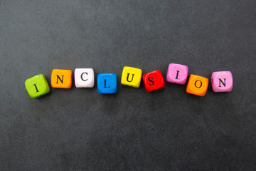 Inclusion text of multi colored cubes on dark background. Inclusive social concept.