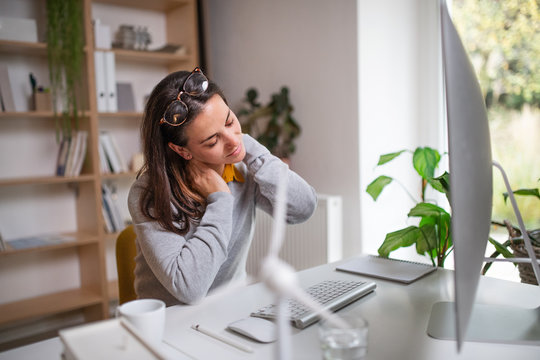 Businesswoman At The Desk Indoors In Office, Feeling Pain In Neck.