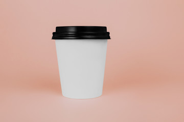 White paper coffee or tea cup with black lid on pink background.  Mockup, coffee to go container.