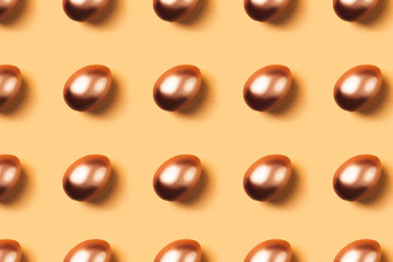 Pattern made of golden eggs on yellow background. Minimal concept. Easter.