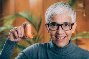 Inhaling Medicine - Senior Woman using an Inhaler with Extension Tube