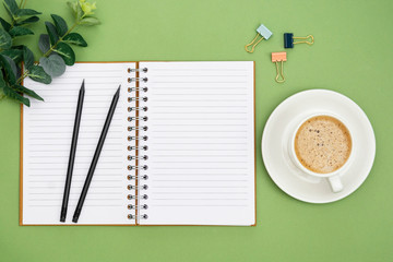 Fototapeta na wymiar Open notebook with empty page and coffee cup. Table top, work space on green background. Creative flat lay.