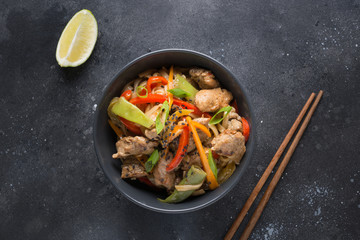 Udon stir-fry noodles with pork and vegetables in black bowl. Asian cuisine.