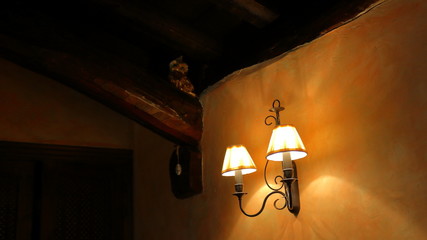 Old lamps turned on in the wall of a dark rustic house at night