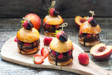 Sweet burgers with brioche bun, chocolate brownie layer, fresh strawberries and melted chocolate sauce. 