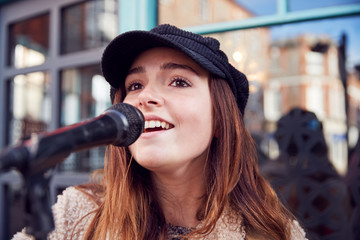 Female Musician Busking Singing Outdoors In Street