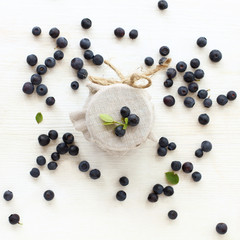 jar with a fabric lid decorated with fresh blueberries top view. natural ingredients for jam