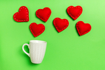 Top view composition of red hearts falling out from a cup on colorful background with copy space. Romantic relationship concept. St Valentaine's Day