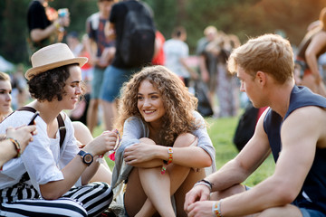 Group of young friends sitting on ground at summer festival.