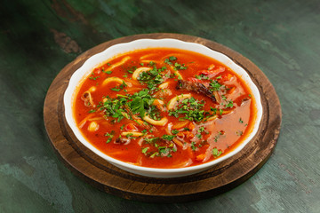 Red meat soup in a white plate on a wooden background