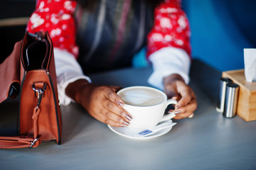 Hands of confident young african american woman in smart casual wear at cafe with cup of cappuccino.