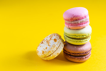 Tasty French macaroons on bright yellow background with copy space for your design. Tasty homemade dessert.