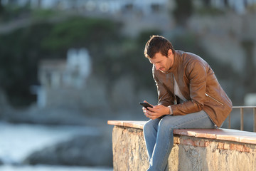 Adult man using phone in a coast town