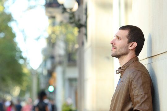 Pensive adult man looking away in the street