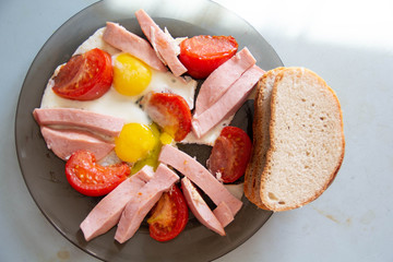 fried eggs with boiled sausage and tomatoes