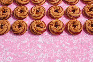 Lots of shortbread cookies with berry jam on a pink background arranged in a rectangular frame