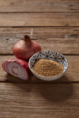 Ground roasted rice and red onion on wooden background.