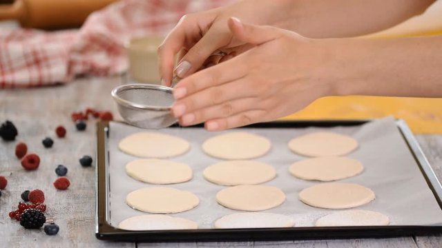 A baker uses a sifter to sprinkle powdered sugar on puff pastry. Making French Mille Feuille at kitchen.