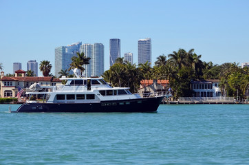 Retro luxury black and white motor yacht,.Riva Alta an exclusive island community city in Miami Beach and the Miami tall building skyline