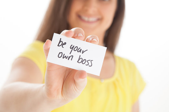 Happy female holding card that says 'be your own boss'