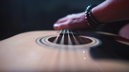 The musician finger touches the strings of an acoustic guitar