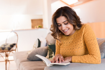 Obraz premium Woman reading book on sofa