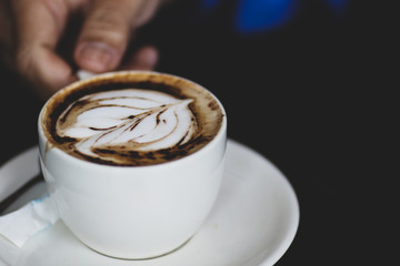 Latte coffee cup at coffee shop. Hand holding coffee cup.