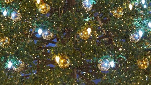Christmas tree with glass ball ornaments and glittering lights illuminated at night, holiday season festive decoration