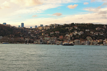 Fototapeta premium Non-touristic part of Istanbul. Different residential buildings on the hills near Bosphorus strait. Winter landscape of the city. View from touristic boat. Istanbul, Turkey