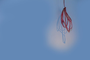 A roll of electrical wire hangs from the ceiling on blue background. Skeins of wires. Harness of power electrical. Cable is required in the renovation of buildings.