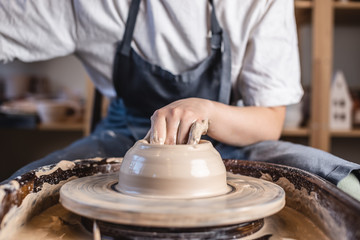 Potter working on a Potter's wheel making a vase. Woman forming the clay with hands creating jug in a workshop. Close up