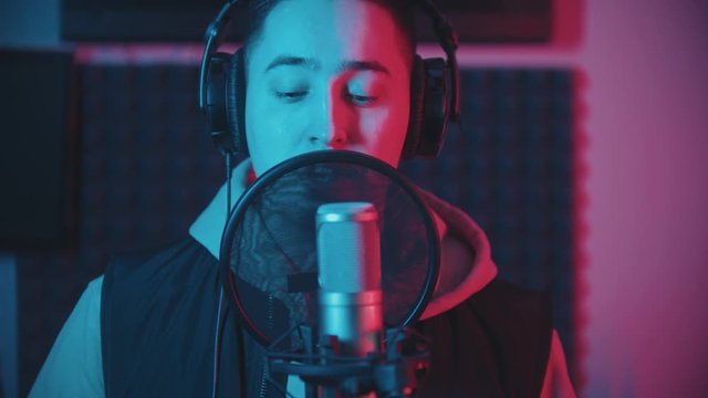 A man rapping in the studio and recording his track