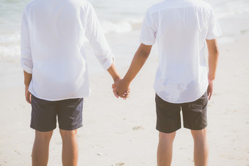 Closeup asian gay couple holding hands together on the beach with relax and leisure in summer, LGBT homosexual legal two man happy and romantic in vacation, relationship sex lover concept.