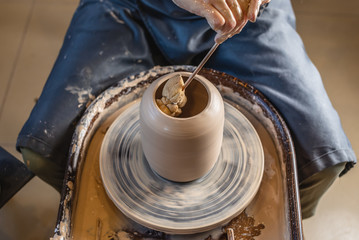 Fototapeta premium Potter working on a Potter's wheel making a vase. Master processing the formed jug giving it the correct shape