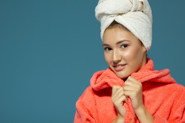 Cheerful attractive funny teen girl with towel on her head, over blue background. Morning beautiful young woman