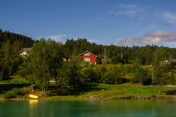 View of the turquoise lake. In the distance can be seen the mountains, boat and house