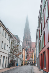 Street view of clock tower of schwerin cathedral with heavy fog in Schwerin near Hamburg, Germany