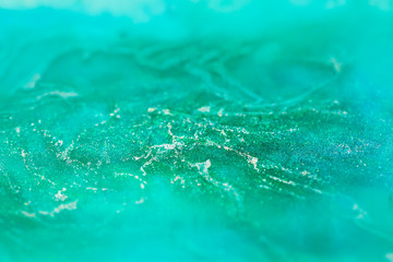 macro shot of alcohol ink with glitter dissolved in water, abstract turquoise background - 318614969