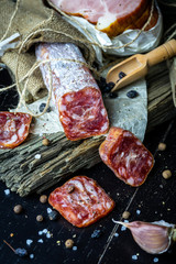 Farm smoked sausage with garlic and spices close-up on old grey boards and black background