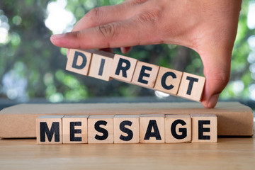 Hand put of word from wooden blocks with letters "Direct Message"