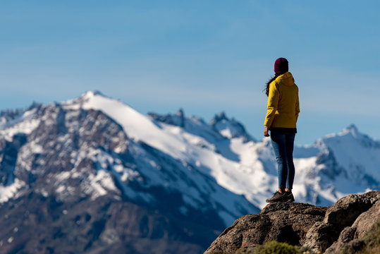 Alone hiker with yellow jacket admiring views over the Andes. Patagonia, Argentina