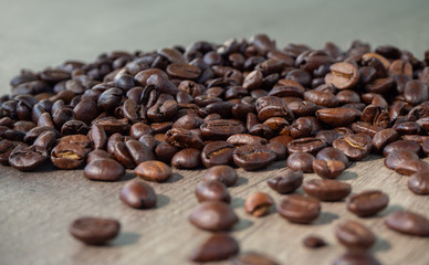 Black coffee in grains on the surface of a wooden table.