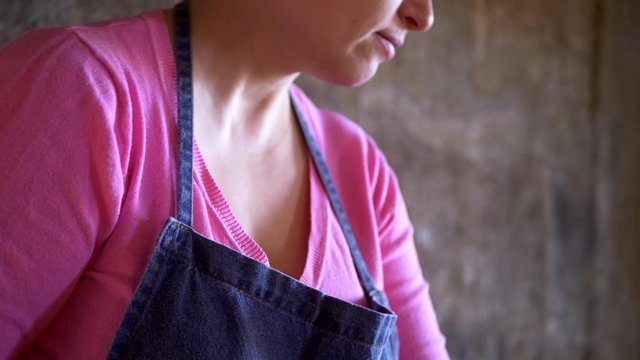 beautiful mature woman in pink sweater and in economic apron stuffs bell peppers with fresh minced pork. girl cuts pepper, onion, prepares sauce and puts minced meat in peppers