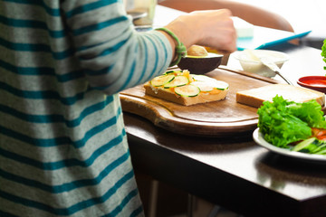 Obraz na płótnie Canvas Girl prepares a toast with salmon, zucchini and avocado cheese