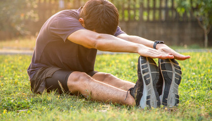 Asian man is stretching after running or work out at evening on yard