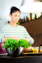 Woman in the kitchen prepares the salad
